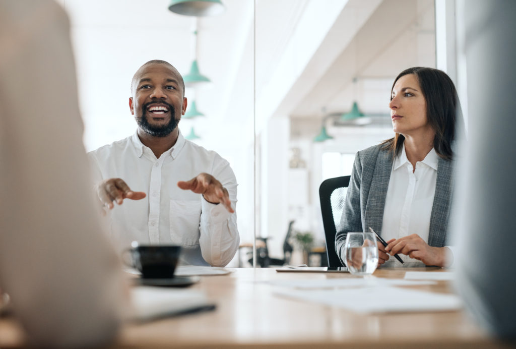 Smiling African American businessman explaining his ideas to a group of coworkers during a meeting together in an office boardroom